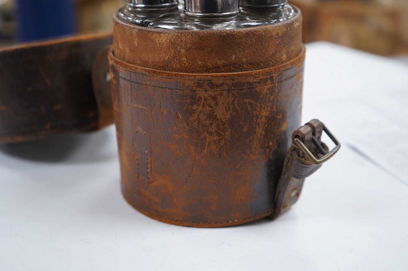 A cased set of four Edwardian silver mounted glass travelling scent bottles, with engraved monogram, George Bedingham, London, 1901, housed in a circular leather carrying case, bottles 14.5cm. Condition - fair to good an